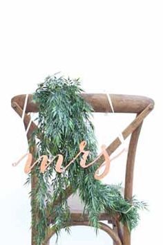 a wooden chair with greenery on it and the word love spelled in cursive letters