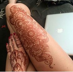 a woman's legs with henna tattoos on them and a laptop in the background