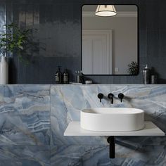 a white sink sitting under a mirror next to a wall mounted faucet in a bathroom