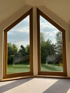 an open window in the corner of a room with grass and trees seen through it