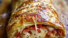 a close up of a pizza roll on a wooden cutting board with cheese and pepperoni