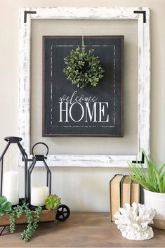 a framed sign that says welcome home next to some potted plants on a table