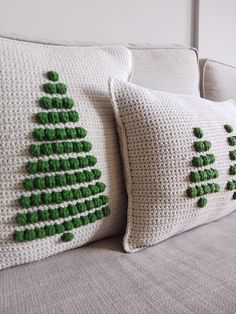 two crocheted christmas tree pillows on a couch