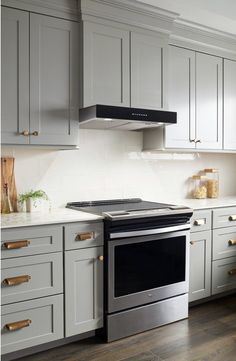 a stove top oven sitting inside of a kitchen next to white cupboards and drawers