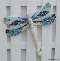 a blue and green dragonfly sitting on top of a white fence