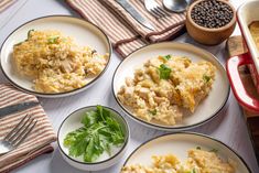 four plates with different types of food on them next to silverware and spoons