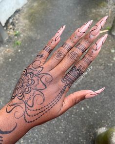 a woman's hand with henna tattoos on her left arm and fingers, in the street