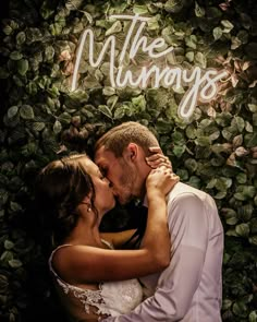 a bride and groom kissing in front of a green wall with the words the munnays on it