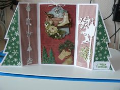 an open christmas card sitting on top of a table with snowflakes and trees