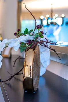 a vase filled with flowers sitting on top of a black table next to a mirror