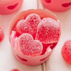 some heart shaped cookies are in a pink bowl on a white table with other hearts