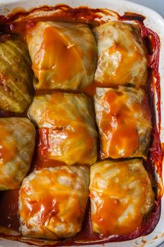 an enchilada casserole in a baking dish with sauce on top