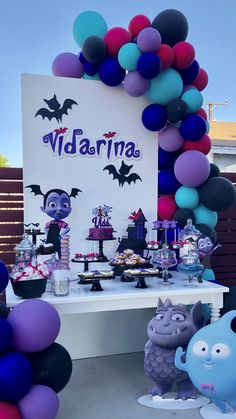 a table topped with lots of balloons and cake