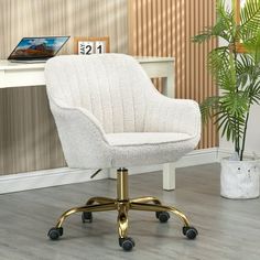 a white office chair sitting on top of a hard wood floor next to a potted plant