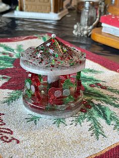 a glass bird feeder sitting on top of a rug next to a christmas tree ornament