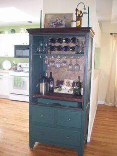 a green cabinet with wine glasses and bottles on it in the middle of a kitchen