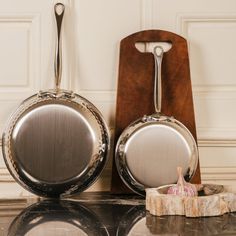 two pans sitting next to each other on top of a marble counter with a cutting board