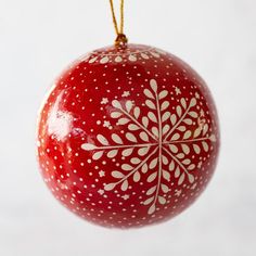 a red ornament hanging from a string on a white background with snowflakes