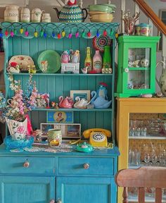 a blue china cabinet with lots of dishes on top of it and glassware in the bottom shelf