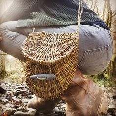 a person sitting on the ground with a basket hanging from their feet and holding something in his hand