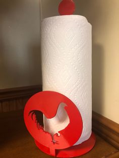 a toilet paper roll holder with a rooster on it and a red circle in the middle