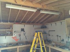 a man standing on a ladder in a room filled with tools and workbenches