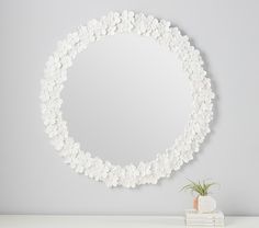 a white circular mirror sitting on top of a table next to a plant and books