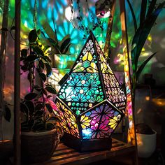 a colorful lamp sitting on top of a wooden shelf next to plants and potted plants