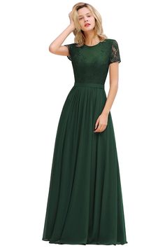 a woman in a long green dress with lace on the top and sleeves, standing against a