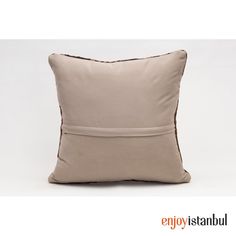 a beige pillow with brown piping on the front and back, sitting against a white background