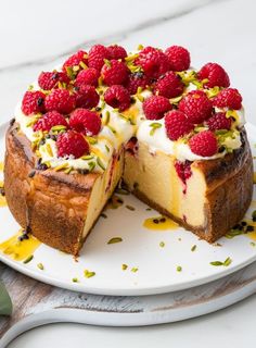 a cheesecake with raspberries and pistachio toppings on a plate