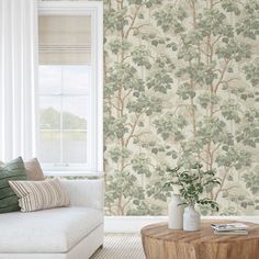 a living room scene with focus on the sofa and wall paper that looks like a tree