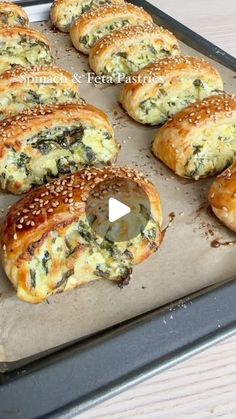 several bagels with cheese and spinach are on a baking sheet