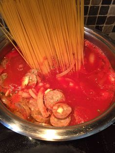 spaghetti being cooked in a pan with tomato sauce