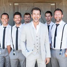 a group of men standing next to each other in front of a wooden door wearing suits