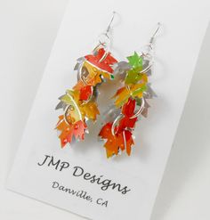 the earrings are made out of metal and have colorful leaves on them with silver earwires