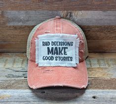 a red hat with the words bad decision make good stories on it sitting against a wooden background