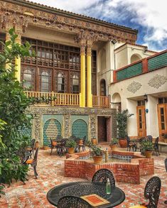 an outdoor dining area with tables and chairs in front of a large, ornate building