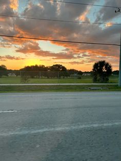 the sun is setting behind some power lines and telephone poles on the side of the road