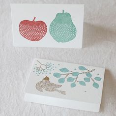 two cards with different designs on them sitting next to each other, one has an apple and the other has a fish