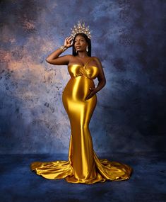 a woman in a gold gown with a crown on her head and hands behind her head