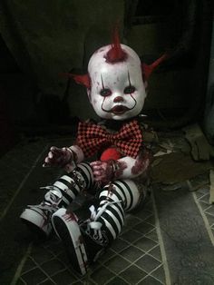 a creepy clown doll sitting on the ground