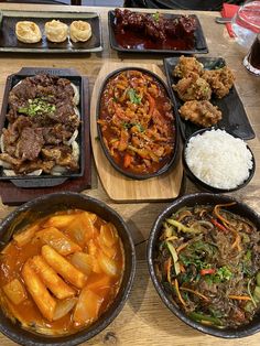 a table topped with bowls filled with different types of food next to rice and meat