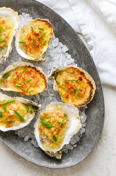 several oysters are on an ice platter with green garnish and seasoning