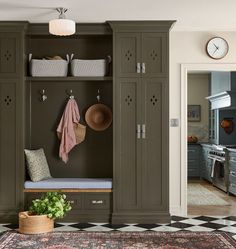 a mud room with green cabinets and baskets on the wall