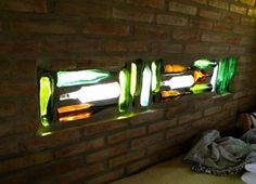 a brick wall with stained glass bottles on it's side and the light shining through them