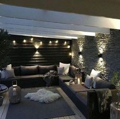 a living room filled with lots of furniture next to a stone wall covered in lights