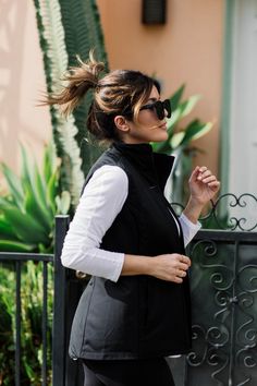 a woman walking down the street with her hair blowing in the wind and sunglasses on