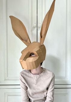 a person sitting down with a paper bunny mask on their head