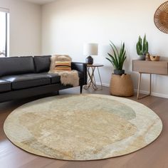 a living room with black leather couches and a round rug on the wooden floor